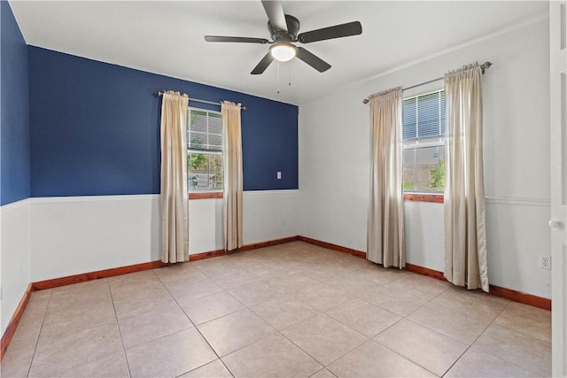 spare room with plenty of natural light, a ceiling fan, baseboards, and light tile patterned floors