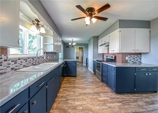 4802 Greenbriar Ln, Everton, AR 72633 - kitchen featuring under cabinet range hood, blue cabinets, a sink, a peninsula, and stainless steel range with electric stovetop