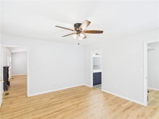 interior space featuring a walk in closet, light wood-style floors, a closet, baseboards, and ensuite bathroom