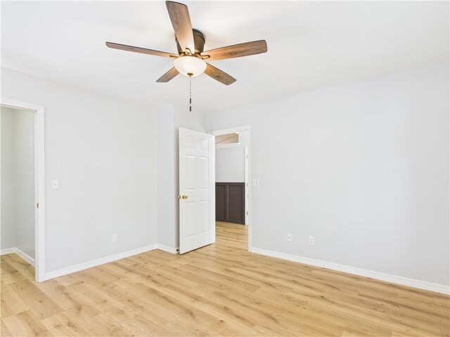 empty room featuring light wood finished floors, baseboards, and ceiling fan