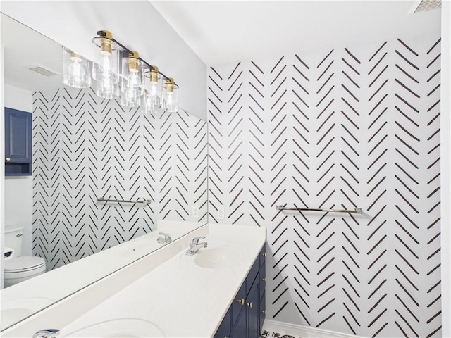 full bath featuring visible vents, a sink, double vanity, and toilet