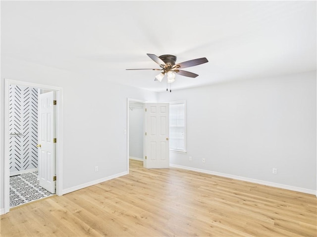 empty room with light wood finished floors, a ceiling fan, and baseboards