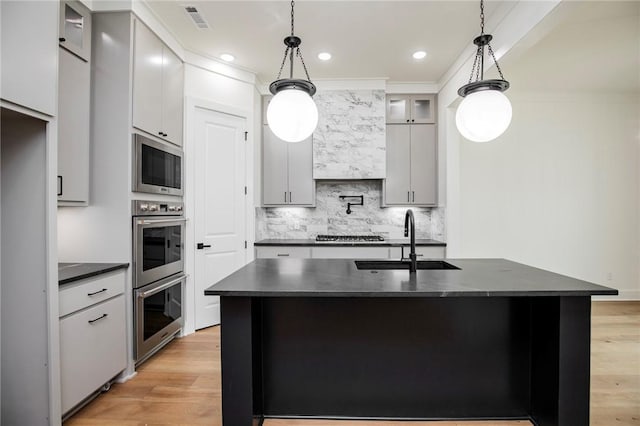 4708 Fieldcrest Ter, Rogers, AR 72758 - kitchen with dark countertops, appliances with stainless steel finishes, light wood-style floors, decorative backsplash, and hanging light fixtures