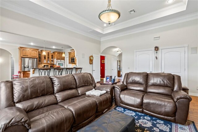 17444 16th Hwy, Siloam Springs, AR 72761 - living room featuring arched walkways, wood finished floors, a raised ceiling, ornamental molding, and recessed lighting