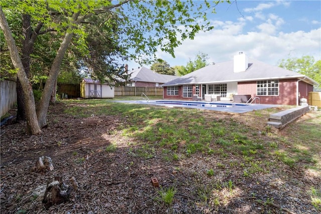 back of house featuring a fenced backyard, an outdoor structure, a fenced in pool, and a storage shed