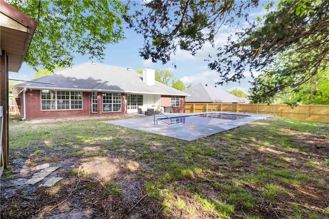 rear view of house featuring a patio area, a chimney, a lawn, a fenced backyard, and a fenced in pool