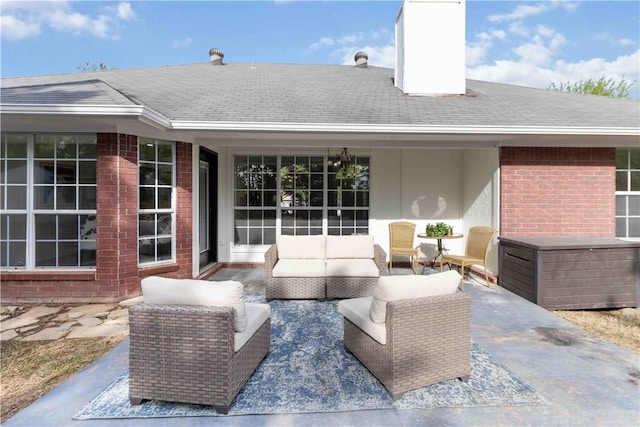 rear view of house with outdoor lounge area, a chimney, roof with shingles, a patio area, and brick siding