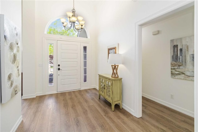 entryway with wood finished floors, baseboards, and an inviting chandelier