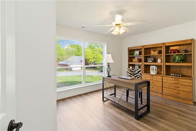 office space featuring baseboards, wood finished floors, a wealth of natural light, and ceiling fan