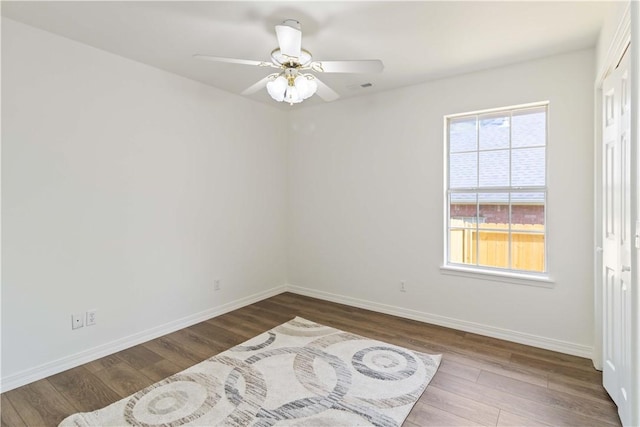empty room with ceiling fan, baseboards, wood finished floors, and visible vents
