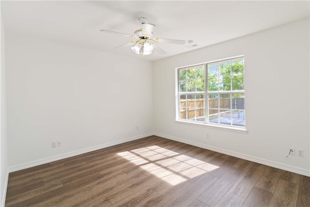 spare room featuring wood finished floors, visible vents, baseboards, and ceiling fan