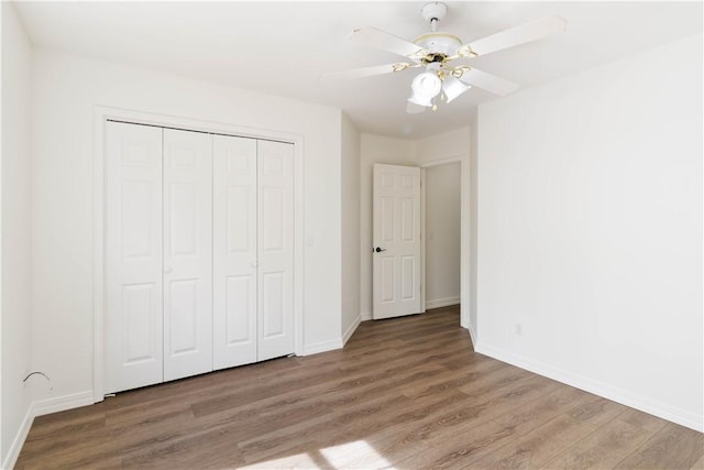 unfurnished bedroom with baseboards, a ceiling fan, wood finished floors, and a closet