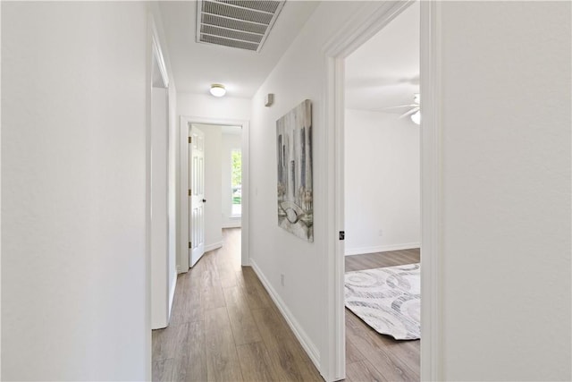 corridor with wood finished floors, visible vents, and baseboards