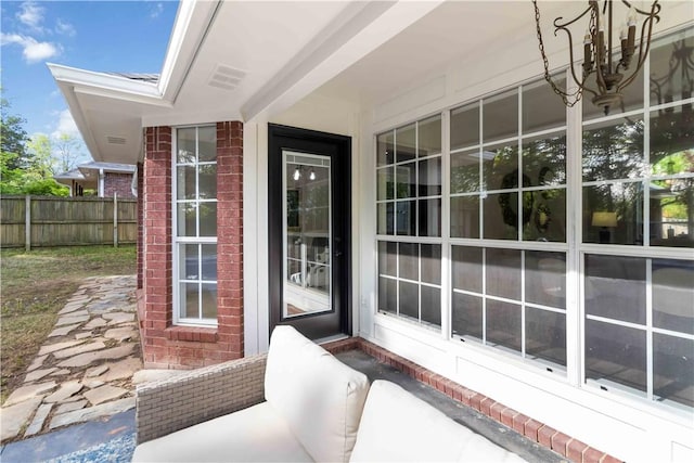 doorway to property with brick siding and fence