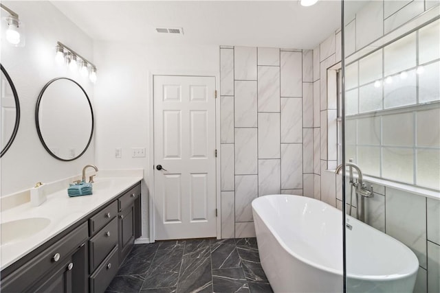 full bath featuring marble finish floor, a freestanding bath, double vanity, visible vents, and a sink