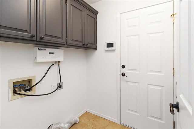 washroom featuring light tile patterned floors, baseboards, washer hookup, and cabinet space