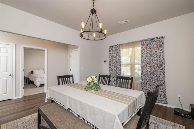 dining area featuring baseboards, wood finished floors, visible vents, and an inviting chandelier