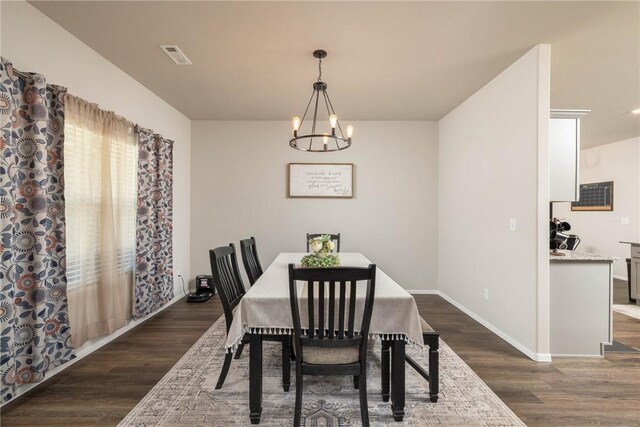 dining room featuring baseboards, visible vents, dark wood-style floors, and a notable chandelier