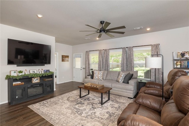 living area with dark wood-type flooring, visible vents, baseboards, and ceiling fan