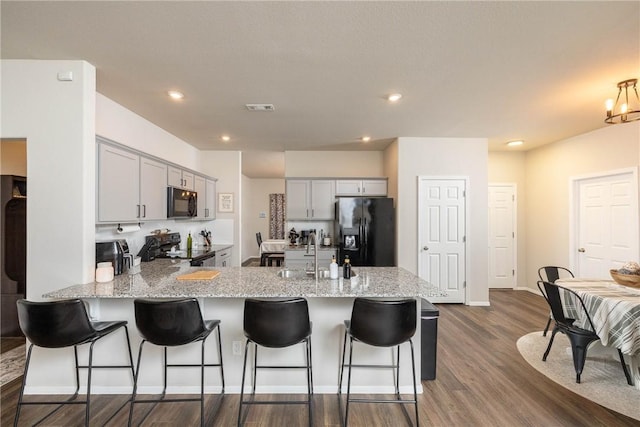 kitchen with a sink, black appliances, gray cabinets, a peninsula, and visible vents