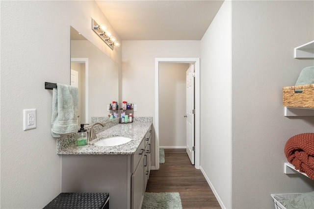 bathroom featuring baseboards, wood finished floors, and vanity