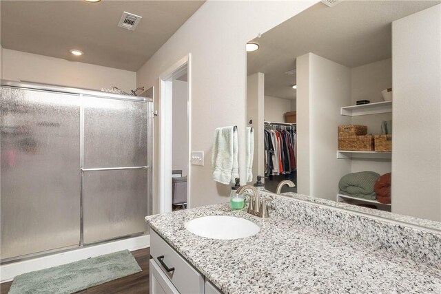 bathroom featuring a shower stall, vanity, wood finished floors, and visible vents