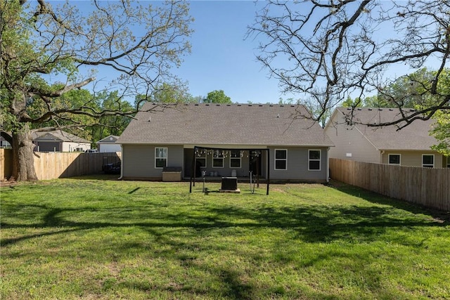 back of house featuring a fenced backyard, roof with shingles, and a yard