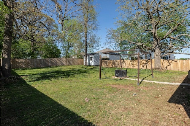 view of yard with a fenced backyard, a storage unit, and an outdoor structure