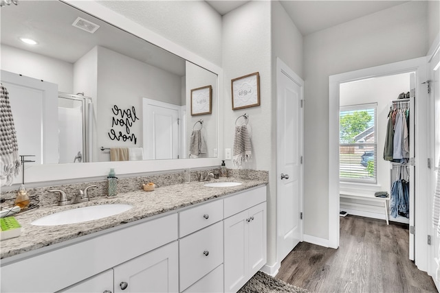 full bath featuring wood finished floors, a sink, visible vents, and double vanity