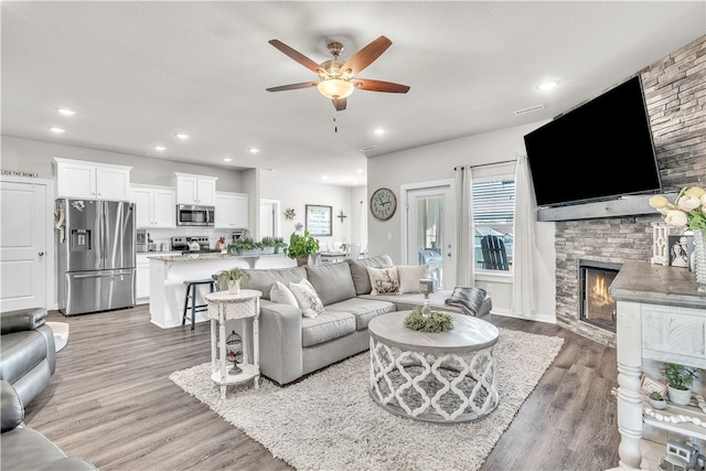 living room with recessed lighting, a ceiling fan, light wood-type flooring, and a fireplace