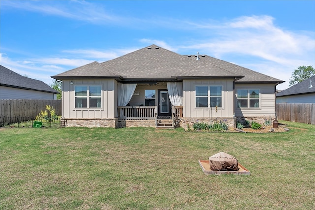 back of house featuring board and batten siding, a shingled roof, and a fenced backyard