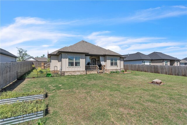 rear view of house with board and batten siding, a fenced backyard, and a yard