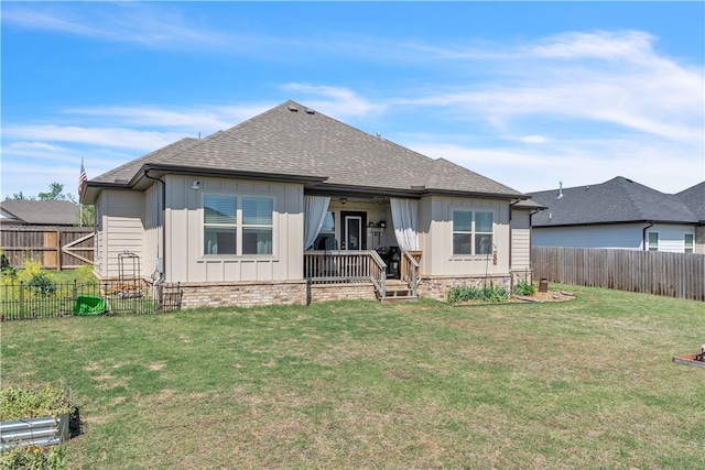 rear view of property featuring board and batten siding, a lawn, a fenced backyard, and roof with shingles