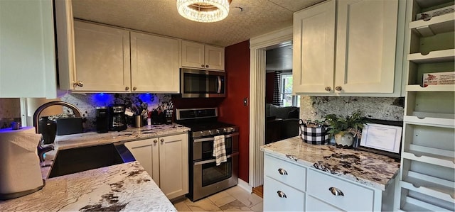 kitchen with tasteful backsplash, a sink, a chandelier, stainless steel appliances, and white cabinetry