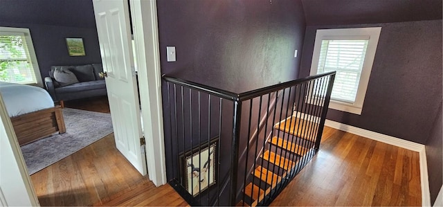 stairs featuring baseboards, wood finished floors, and a wealth of natural light