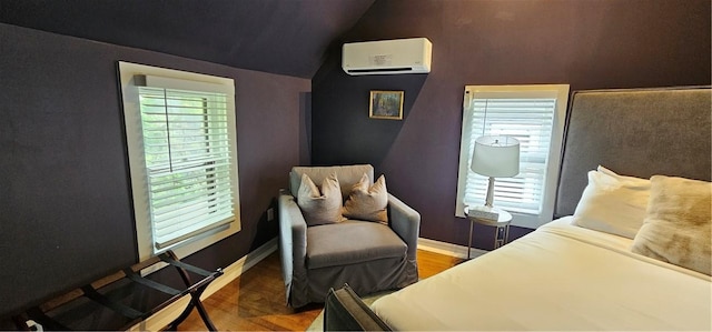bedroom with vaulted ceiling, wood finished floors, an AC wall unit, and baseboards