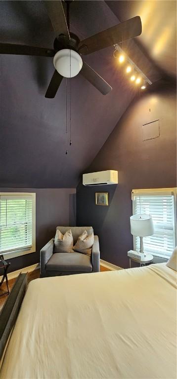 bedroom with a wall mounted air conditioner, rail lighting, vaulted ceiling, and wood finished floors