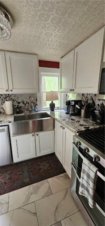kitchen with a sink, an ornate ceiling, white cabinetry, marble finish floor, and appliances with stainless steel finishes