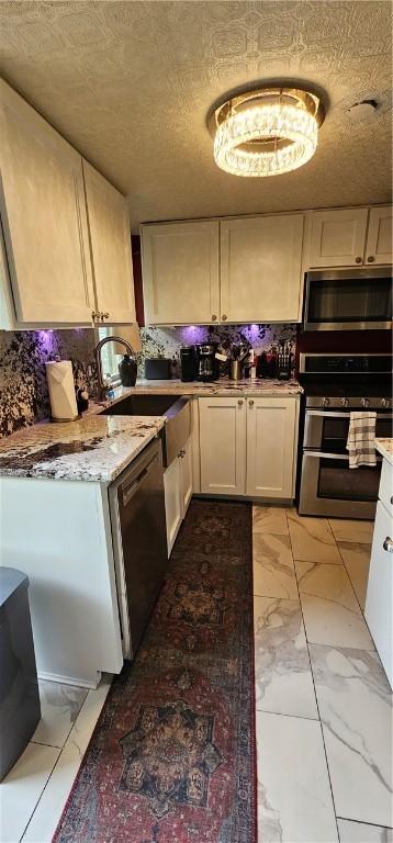 kitchen with white cabinets, marble finish floor, a sink, tasteful backsplash, and appliances with stainless steel finishes