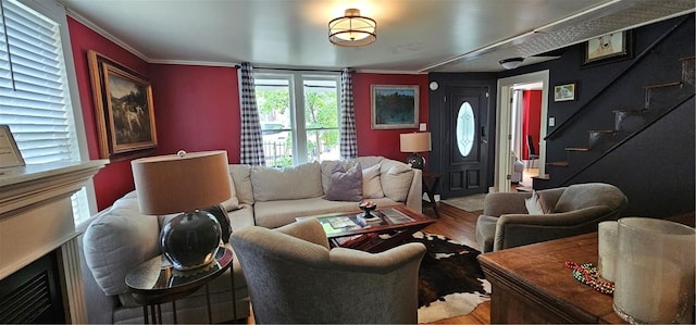 living area featuring wood finished floors, crown molding, and stairs