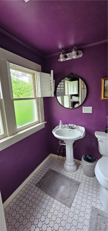 half bath featuring crown molding, toilet, and baseboards