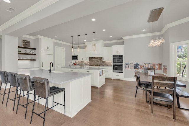 kitchen featuring a spacious island, white cabinetry, decorative backsplash, open shelves, and appliances with stainless steel finishes