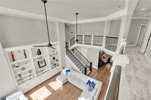 living area with light wood finished floors, baseboards, visible vents, stairs, and ceiling fan