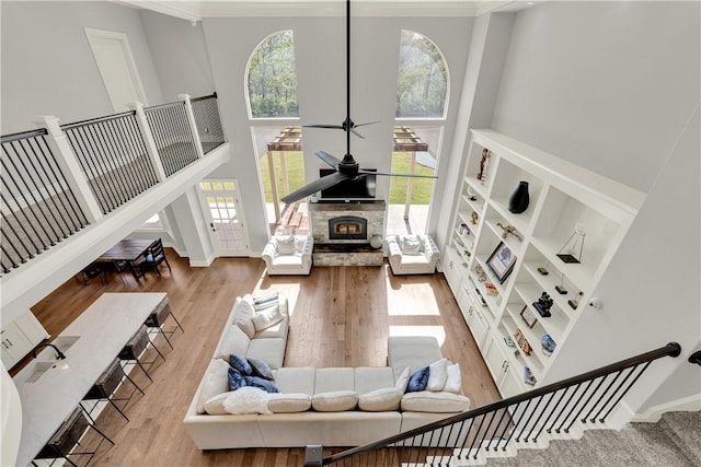 living area with wood finished floors, a high ceiling, stairway, and crown molding