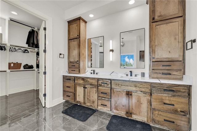 full bath featuring a sink, double vanity, baseboards, a spacious closet, and recessed lighting