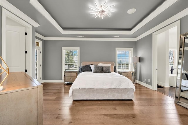 bedroom featuring a raised ceiling, baseboards, hardwood / wood-style flooring, and a notable chandelier