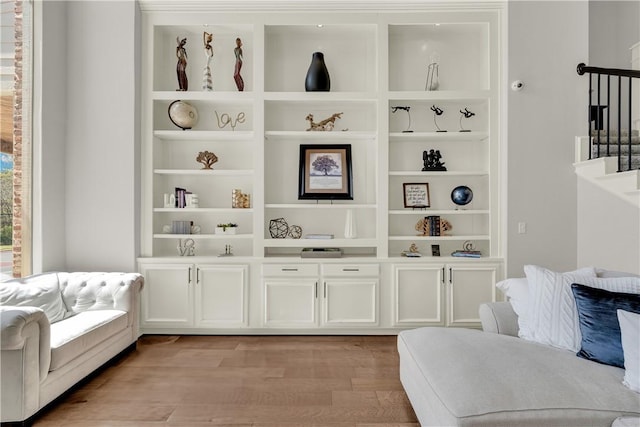 living area with stairway, built in features, and light wood-style floors