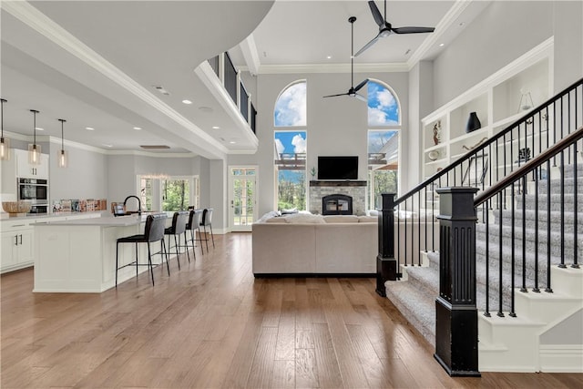 living room featuring light wood-type flooring, recessed lighting, a ceiling fan, stairs, and a fireplace
