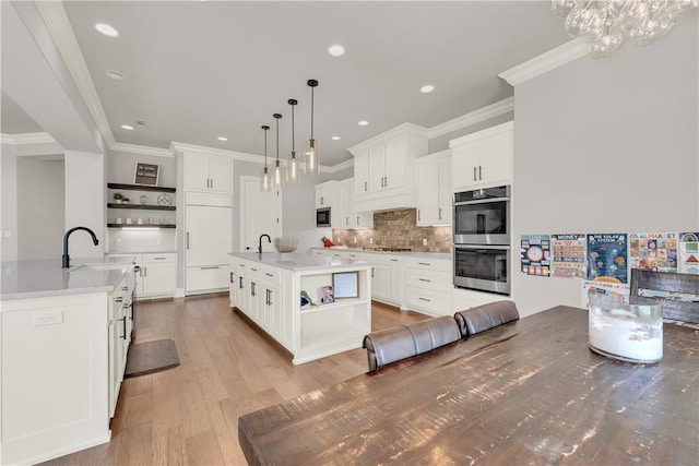 kitchen featuring open shelves, double oven, ornamental molding, and a sink
