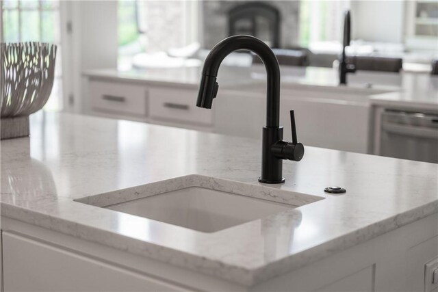 details with light stone countertops, white cabinetry, and a sink